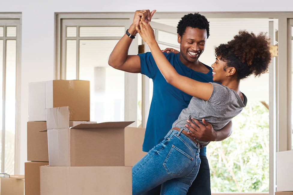 man and woman dancing next to moving boxes in a living room