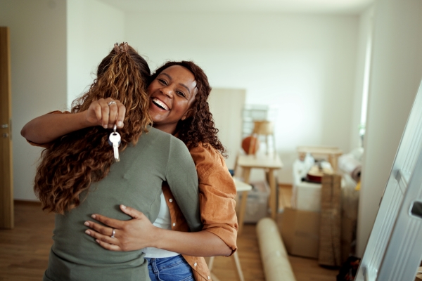 two young women hugging each other in their new home