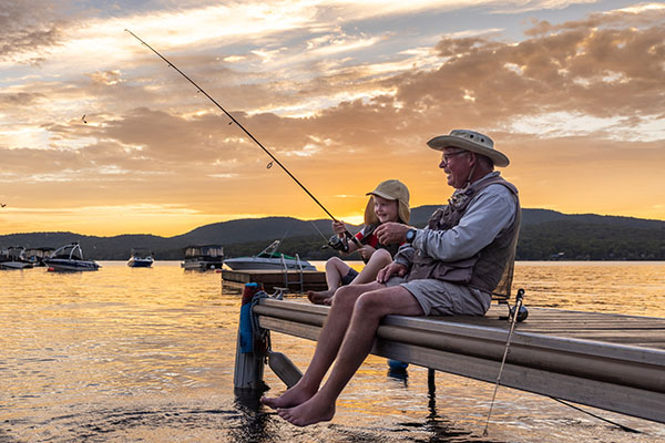 grandpa and grandson sitting on a wood dock fishing