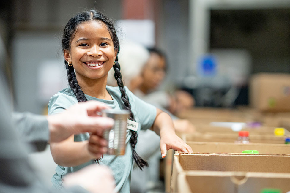 mixed-race girl packing donations at a local food bank